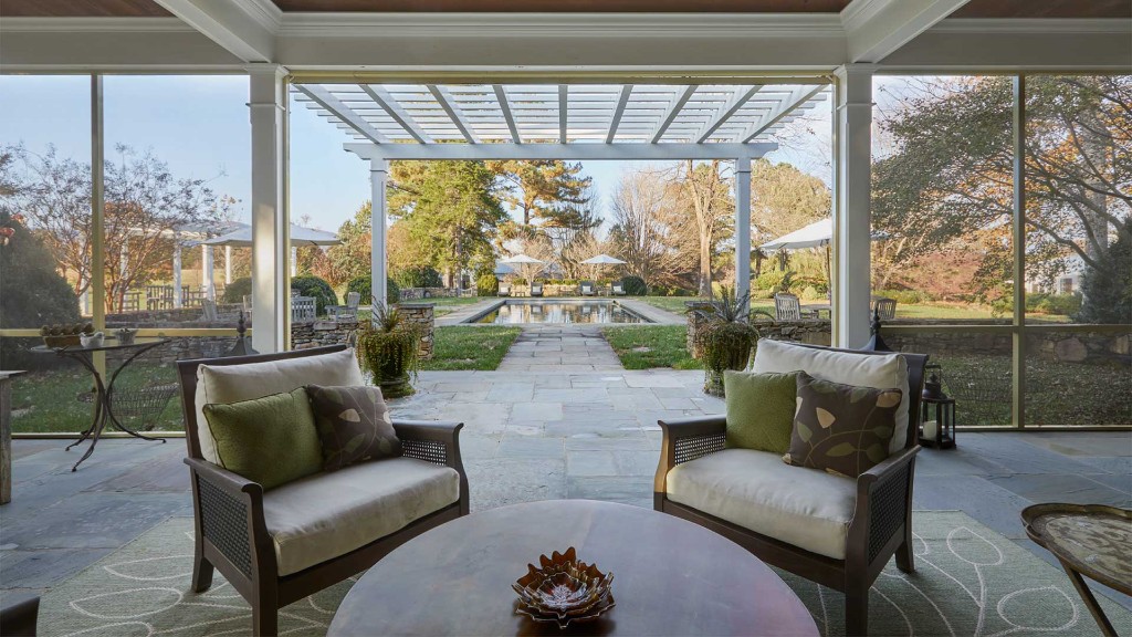 Screened porch overlooking pool and landscaped backyard at a Charlottesville area vacation rental
